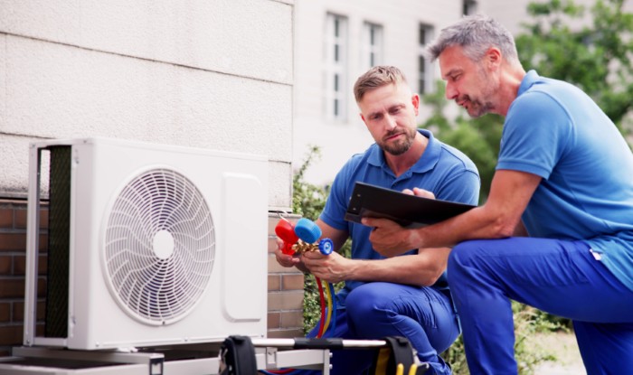 HVAC technicians reviewing an outdoor air conditioning unit in Glendale, AZ