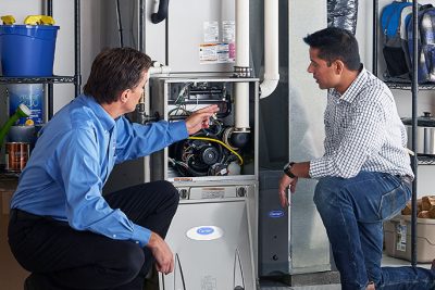 HVAC technician explaining furnace repair and maintenance to a homeowner in Glendale, AZ