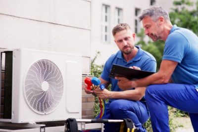 HVAC technicians reviewing an outdoor air conditioning unit in Glendale, AZ